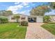 Charming home featuring awning-covered windows, a carport and a brick driveway, all beautifully landscaped at 25605 Belle Alliance, Leesburg, FL 34748