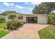 Charming home featuring awning-covered windows, a carport, a brick driveway, and mature trees in the community at 25605 Belle Alliance, Leesburg, FL 34748