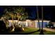 Well-lit house at night with beautiful landscaping, blue shutters, golf cart, and a paver driveway at 26148 Glen Eagle Dr, Leesburg, FL 34748