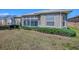 Back view of house with an enclosed lanai, a manicured yard, and trimmed hedges at 320 Bentwood Dr, Leesburg, FL 34748