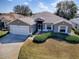 Inviting home featuring a two-car garage, neat landscaping, and a well-maintained front yard at 320 Bentwood Dr, Leesburg, FL 34748