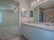 Bathroom with double sink vanity, large mirror, and tiled walk-in shower with grab bars at 32708 Westwood Loop, Leesburg, FL 34748