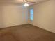 Neutral carpeted bedroom with ceiling fan and a window for natural light at 32708 Westwood Loop, Leesburg, FL 34748