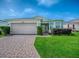 Well-kept one-story home with attached two-car garage, brick driveway and lush green lawn at 32708 Westwood Loop, Leesburg, FL 34748