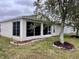 Rear view of home shows sunroom addition, attractive landscaping, and mature shade tree at 32708 Westwood Loop, Leesburg, FL 34748