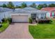 Charming single-story home featuring a two-car garage, brick driveway, and manicured lawn at 32708 Westwood Loop, Leesburg, FL 34748