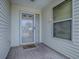 Covered front porch with tile flooring, glass-paned door and a 'Welcome' mat at 32708 Westwood Loop, Leesburg, FL 34748