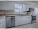 Bright kitchen featuring stainless steel appliances, white cabinets, and tiled countertops at 32708 Westwood Loop, Leesburg, FL 34748
