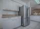Kitchen area featuring stainless steel refrigerator, white cabinets, and tiled flooring at 32708 Westwood Loop, Leesburg, FL 34748