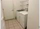 A bright laundry room featuring a washer, dryer, tile flooring, and convenient overhead shelving at 32708 Westwood Loop, Leesburg, FL 34748