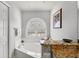 Bright bathroom featuring a tub with granite countertops and an arched window at 39136 Harbor Hills Blvd, Lady Lake, FL 32159