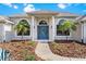 Elegant front entrance with a blue door, columns, palm trees, and well-kept landscaping at 39136 Harbor Hills Blvd, Lady Lake, FL 32159