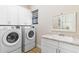 Laundry room with modern washer and dryer, storage cabinets, and sink, designed for efficient home chores at 5413 Sandy Hill Ln, Lady Lake, FL 32159