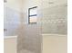 Modern walk-in shower featuring neutral tile, glass enclosure, and a decorative tile accent stripe at 5413 Sandy Hill Ln, Lady Lake, FL 32159