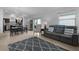 Open-concept living room featuring a gray sofa, patterned rug, and sliding glass doors with natural light at 5597 Gracie Ln, The Villages, FL 32163