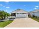 Charming single-story home with a well-manicured lawn, white picket fence, and two-car garage at 6051 Chase Ct, The Villages, FL 32163