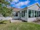 Rear exterior view of the home showcasing the enclosed sunroom, glass door, and lawn at 610 Mallory Hill Dr, The Villages, FL 32162