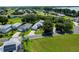 Aerial view of homes with well-maintained lawns, mature trees, and a glimpse of a lake in the background at 6250 Sailboat Ave, Tavares, FL 32778