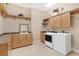 Well-equipped laundry room featuring light wood cabinets, folding counter and modern washer and dryer at 631 Old Mount Dora Rd, Eustis, FL 32726