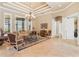 Bright living room featuring large windows, travertine floors, tray ceiling, and elegant furnishings at 631 Old Mount Dora Rd, Eustis, FL 32726