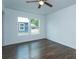 Bright bedroom features dark vinyl floors, ceiling fan, a window overlooking the backyard, and white walls at 654 Nw 9Th Ave, Webster, FL 33597