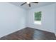 Bright bedroom features dark vinyl floors, ceiling fan, a window overlooking the trees, and white walls at 654 Nw 9Th Ave, Webster, FL 33597