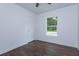 Bright bedroom features dark vinyl floors, ceiling fan, a window overlooking the trees, and white walls at 654 Nw 9Th Ave, Webster, FL 33597