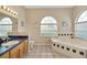 Bright bathroom with a soaking tub under an arched window and a vanity with a sink at 726 Grand Vista Trl, Leesburg, FL 34748