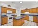 Open kitchen featuring wood cabinets, blue countertops, a center island, and white appliances at 726 Grand Vista Trl, Leesburg, FL 34748