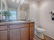 Bathroom features a wood vanity with a sink, white toilet, and large mirror at 796 Elliott Ave, The Villages, FL 32163