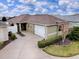 Aerial view of a well-manicured single-story home featuring a two-car garage, green lawn, and tidy landscaping at 796 Elliott Ave, The Villages, FL 32163