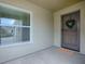 Cozy covered front porch featuring neutral paint and a charming wreath hanging on the front door at 796 Elliott Ave, The Villages, FL 32163