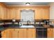 Close up on kitchen sink, wooden cabinets, dark countertops and mosaic tile backsplash at 8373 Se 177Th Bartram Loop, The Villages, FL 32162