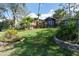 Well-manicured backyard featuring lush green grass, mature trees, and a charming patio seating area at 840 2Nd St, Clermont, FL 34711