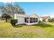 Backyard featuring a lawn and a screened-in porch, set against a bright blue sky at 901 Chula Ct, The Villages, FL 32159