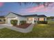 Charming single story home with white siding, tidy landscaping, and an attached garage at dusk at 901 Chula Ct, The Villages, FL 32159