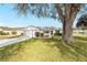 Well-manicured front lawn with mature tree shading this cozy home with covered front porch at 901 Chula Ct, The Villages, FL 32159