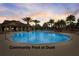 Community pool at dusk with palm trees silhouetted against a vibrant sunset sky at 977 Timberview Rd, Clermont, FL 34715