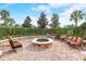 Inviting brick firepit area with comfortable seating perfect for gatherings, surrounded by lush landscaping and palm trees at 977 Timberview Rd, Clermont, FL 34715