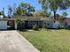 Charming one-story house features a carport and a well-manicured front lawn adorned with lush trees at 100 W Idlewild Ave, Eustis, FL 32726