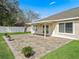 Paver patio with covered porch leads to large, grassy yard—perfect for outdoor entertaining at 10230 Barrington Ct, Leesburg, FL 34788