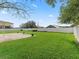 Expansive back yard with white vinyl fence, green grass, and view of the neighborhood at 10230 Barrington Ct, Leesburg, FL 34788