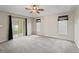 Bright bedroom with neutral carpet, a ceiling fan, and slider leading to the lanai at 10230 Barrington Ct, Leesburg, FL 34788