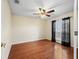 Spacious bedroom with hardwood floors, ceiling fan, and a window with black curtains providing natural light at 10230 Barrington Ct, Leesburg, FL 34788