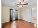 Bedroom featuring hardwood floors, natural light from the window, ceiling fan, and an open doorway at 10230 Barrington Ct, Leesburg, FL 34788