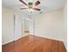 Spacious bedroom with hardwood floors, ceiling fan, and natural light, with an open doorway to the hallway at 10230 Barrington Ct, Leesburg, FL 34788