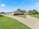 Single-story home featuring a long driveway, manicured lawn, vibrant blue shutters, and a two-car garage at 10230 Barrington Ct, Leesburg, FL 34788