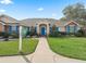 Inviting single-story home with attractive blue shutters, lush landscaping, and a welcoming front entrance at 10230 Barrington Ct, Leesburg, FL 34788