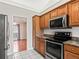 Well-lit kitchen with stainless steel appliances, wood cabinetry and white tile floors at 10230 Barrington Ct, Leesburg, FL 34788