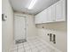 Functional laundry room featuring tile flooring and ample cabinet storage at 10230 Barrington Ct, Leesburg, FL 34788